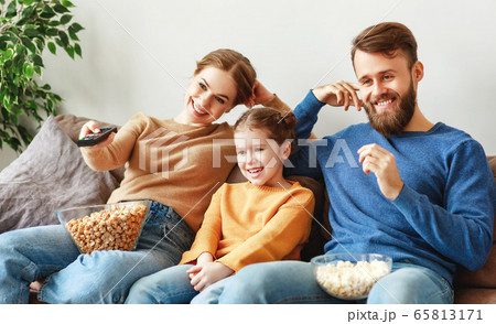 Happy family resting with snacks on couch at home. Happy family resting with snacks on couch at home. 65813171