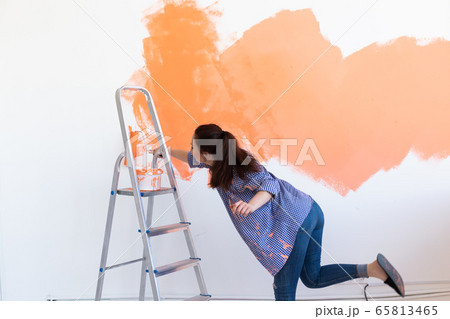 Renovation, redecoration and repair concept - Cheerful woman painting wall in new home. 65813465
