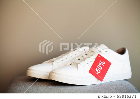 Pair of new stylish white sneakers on floor at store. 65816271