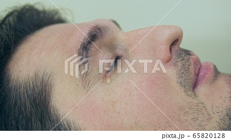 High quality close-up of a man laying on a couch and crying during the treatment. Male tears closeup video. 65820128
