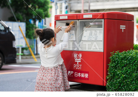 ポストに手紙を投函する女の子の写真素材