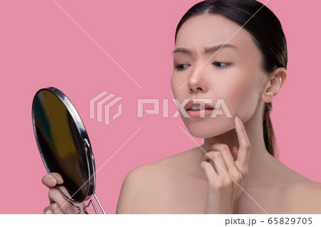 Worried dark-hairfed asian girl looking and the mirror Worried dark-hairfed asian girl looking and the mirror 65829705
