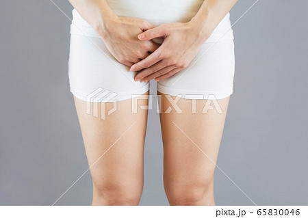 woman wore white shorts put her hand on the genitalia area.female with hands holding her Penis in pain.Health-care Concept.Selective focus isolated on gray background 65830046