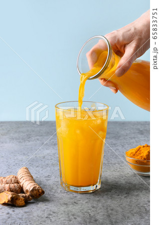 Pouring golden turmeric iced beverage. 65833751