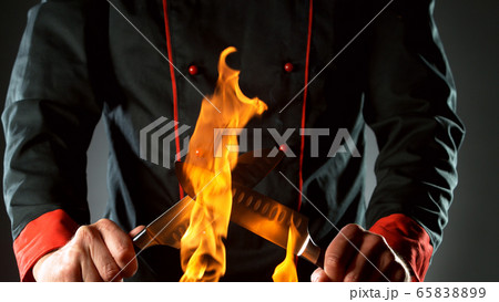 Closeup of chef holding knives in fire Closeup of chef holding knives in fire 65838899