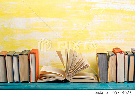Composition with vintage old hardback books, diary, fanned pages on wooden deck table and abstract background. Books stacking. Back to school. Copy Space. Education background. Composition with vintage old hardback books, diary, fanned pages on wooden deck table and abstract background. Books stacking. Back to school. Copy Space. Education background. 65844622