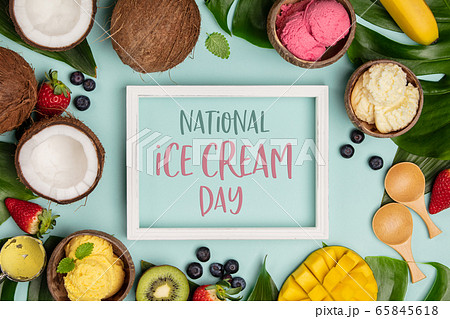 National ice cream day 19 july concept. Tropical fruits and plants with variety of ice cream in coconut shells on blue background 65845618