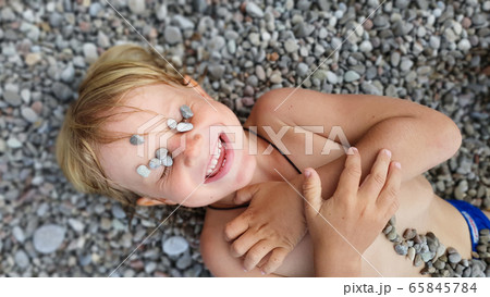 On sunny beach kids lying on pebble, warming after On sunny beach kids lying on pebble, warming after 65845784