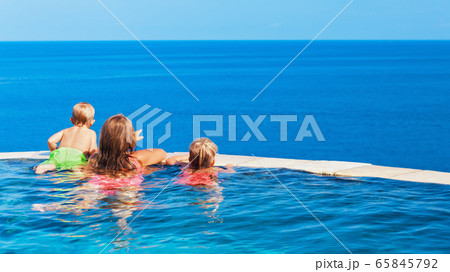 Kids at edge of infinity swimming pool with sea 65845792