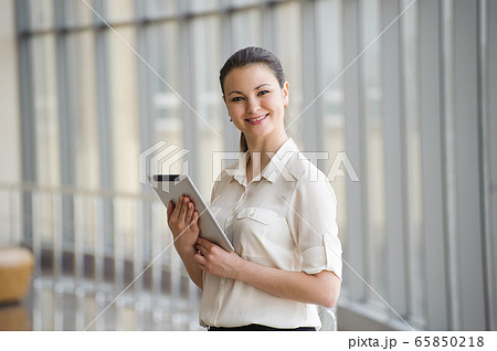 Young businesswoman talking on mobile phone while standing by window in office. 65850218