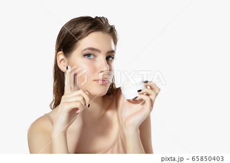 Youth secrets. Close up of beautiful young woman with moisturizer over white background. Cosmetics and makeup, natural and eco treatment, skin care. 65850403