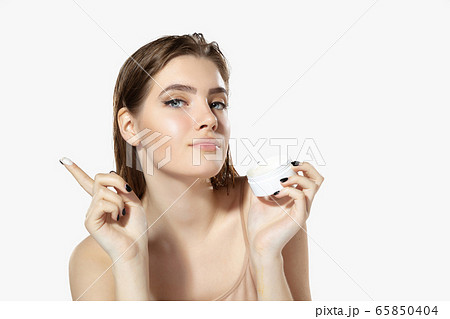 Youth secrets. Close up of beautiful young woman with moisturizer over white background. Cosmetics and makeup, natural and eco treatment, skin care. 65850404