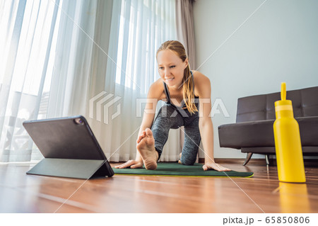 Fitness woman exercising on the floor at home and watching fitness videos in a tablet. People do Fitness woman exercising on the floor at home and watching fitness videos in a tablet. People do 65850806