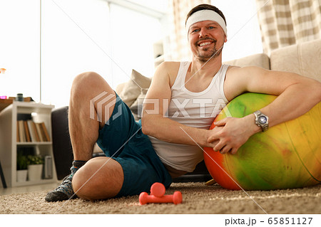 Man sitting at home carpet near ball and dumbbells 65851127