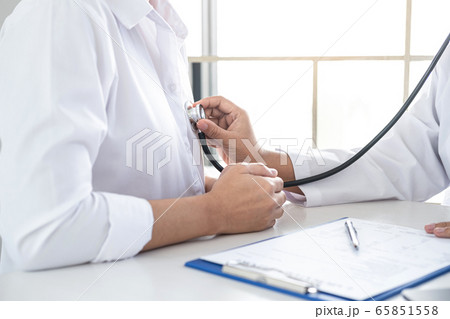 Doctor using a stethoscope checking patient with 65851558