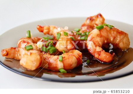 Large pacific shrimps in sweet and sour sauce with chopped green onions on a glass plate. Large pacific shrimps in sweet and sour sauce with chopped green onions on a glass plate. 65853210
