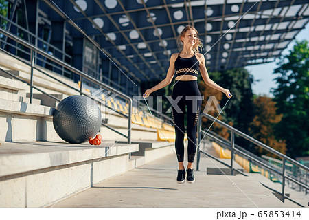 fitness and lifestyle concept - woman doing sports outdoors. girl with skipping rope. 65853414