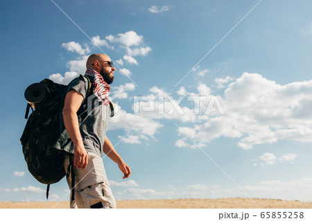 Man with backpack traveling through the desert Man with backpack traveling through the desert 65855258
