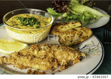 Fried fish with vegetables and piece of lemon on ceramic plate. 65862007