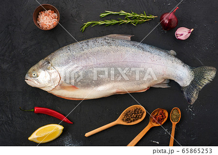 Raw tasmanian ocean trout with spice and herbs on black concrete background Raw tasmanian ocean trout with spice and herbs on black concrete background 65865253