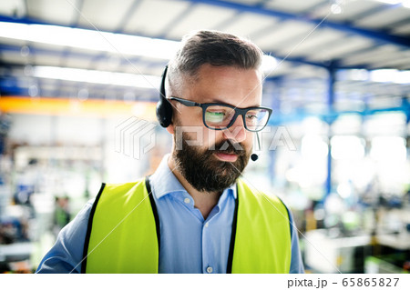Front view of technician or engineer with headset standing in industrial factory. 65865827