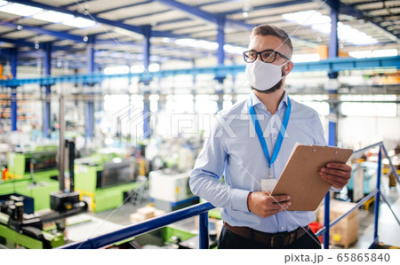 Technician or engineer with protective mask working in industrial factory, standing. 65865840