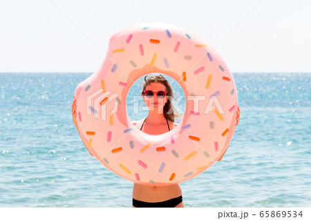Beautiful woman is playing with donut rubber ring Beautiful woman is playing with donut rubber ring 65869534