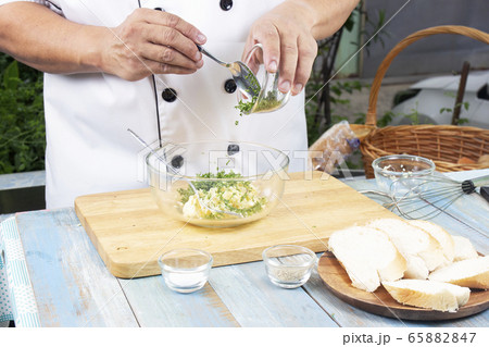 Chef putting minced parsley to bowl for cook 65882847