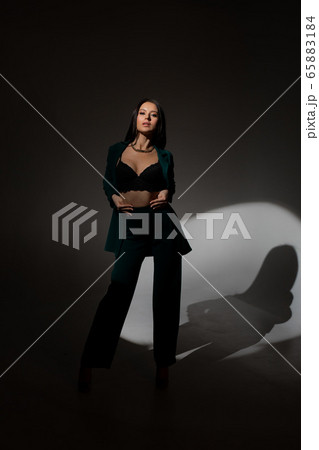 Studio photo of pretty brunette woman in twilight in bra looks into the distance Studio photo of pretty brunette woman in twilight in bra looks into the distance 65883184