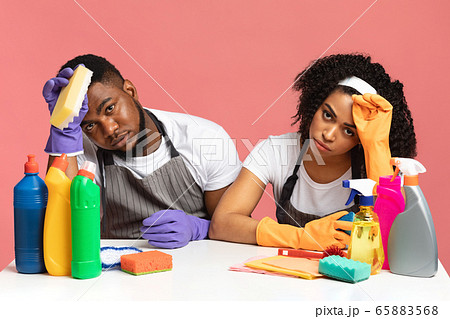 Household Stress. Exhausted couple sitting at table among detergents and cleaning tools 65883568