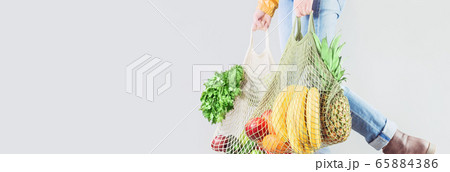 Unrecognizable girl holds two mesh shopper bags 65884386