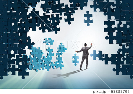 Businessman breaking the wall of jigsaw puzzle Businessman breaking the wall of jigsaw puzzle 65885792