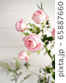 Branch with pink roses on a white natural wooden background 65887660