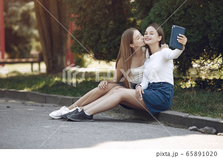 Two elegant and stylish girls in a spring park Two elegant and stylish girls in a spring park 65891020