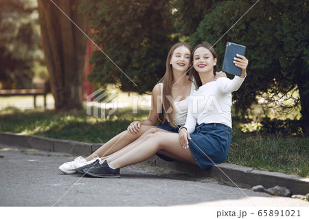 Two elegant and stylish girls in a spring park Two elegant and stylish girls in a spring park 65891021