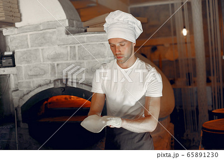 Chef in a white uniform prepare a pizzaa 65891230