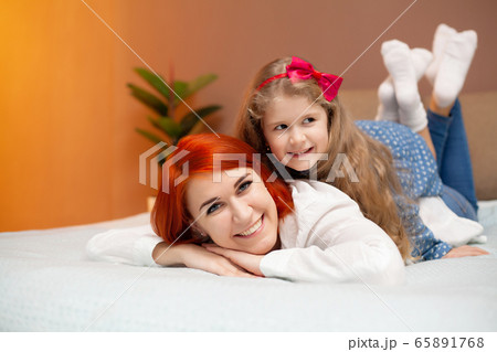 Mother and her baby daughter girl on bed in bedroom. 65891768