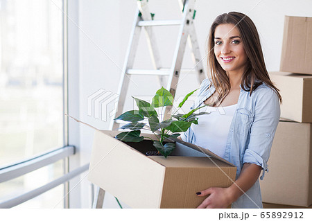 Happy Young Adult Woman Holding Moving Boxes In Empty Room In A New House. Happy Young Adult Woman Holding Moving Boxes In Empty Room In A New House. 65892912