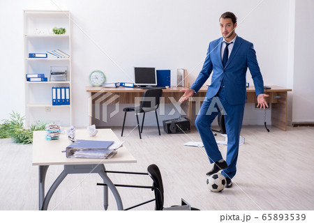 Young male employee playing football in the office Young male employee playing football in the office 65893539