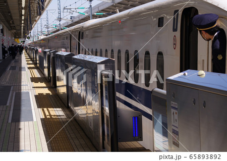 鉄道 安全確認をする新幹線の男性車掌と閉まり始めるホームドアの写真素材 6532