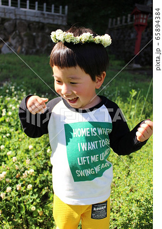 シロツメクサの花冠を頭に乗せた笑顔の男の子の写真素材