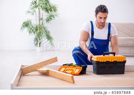 Young male contractor installing furniture at home Young male contractor installing furniture at home 65897888