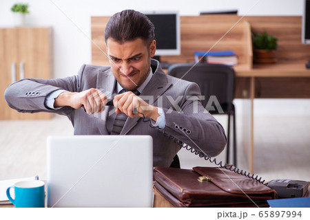 Young male employee unhappy with excessive work 65897994