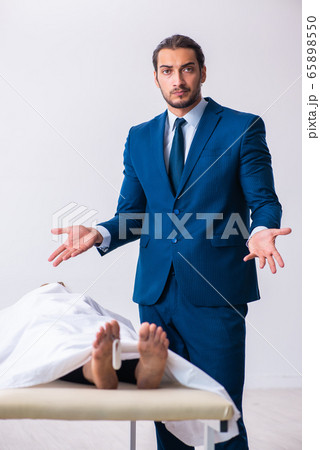 Police coroner examining dead body corpse in morgue 65898550
