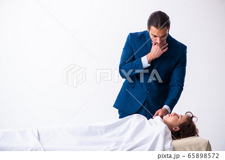 Police coroner examining dead body corpse in morgue 65898572