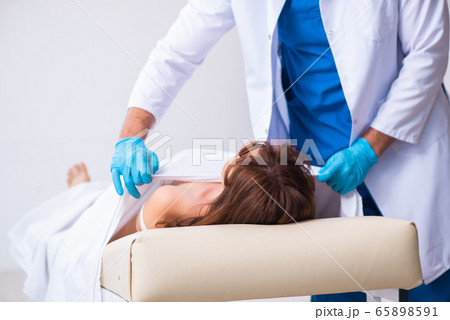 Police coroner examining dead body corpse in morgue 65898591