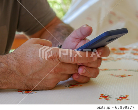 Closeup image of a man holding, using smart phone 65899277