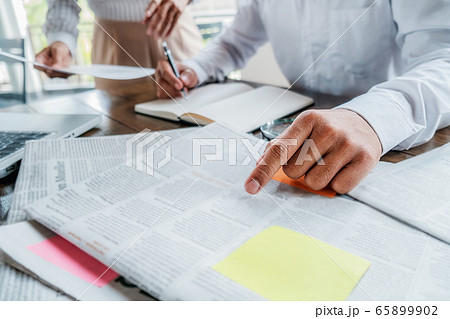 Young unemployed is searching for a job in the newspaper and laptop. 65899902