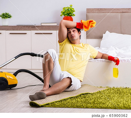 Young handsome man cleaning in the bedroom Young handsome man cleaning in the bedroom 65900362