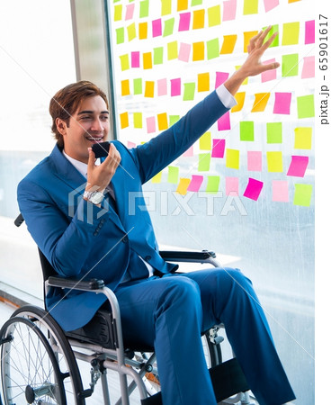 Young handsome man in wheelchair with many conflicting prioritie 65901617